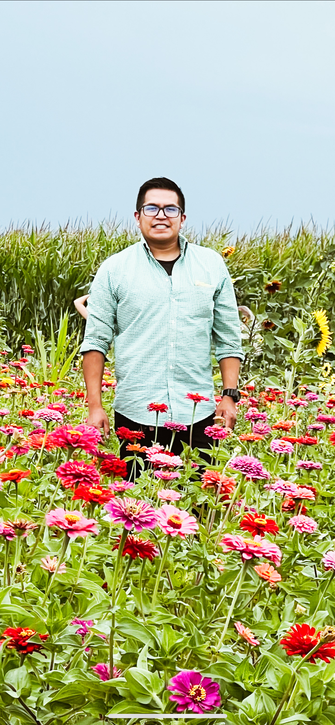 Danny standing in a field of pink and red flowers.