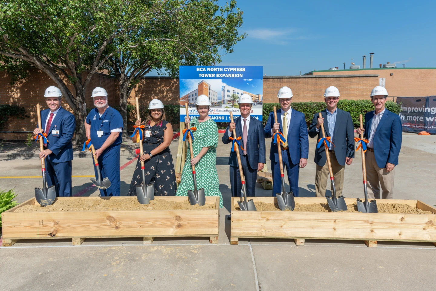 Colleagues wearing hard hats and holding shovels