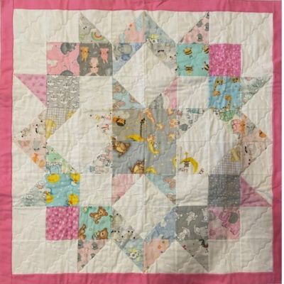 A mostly pink blue and white star pattern baby quilt that Rachel has made