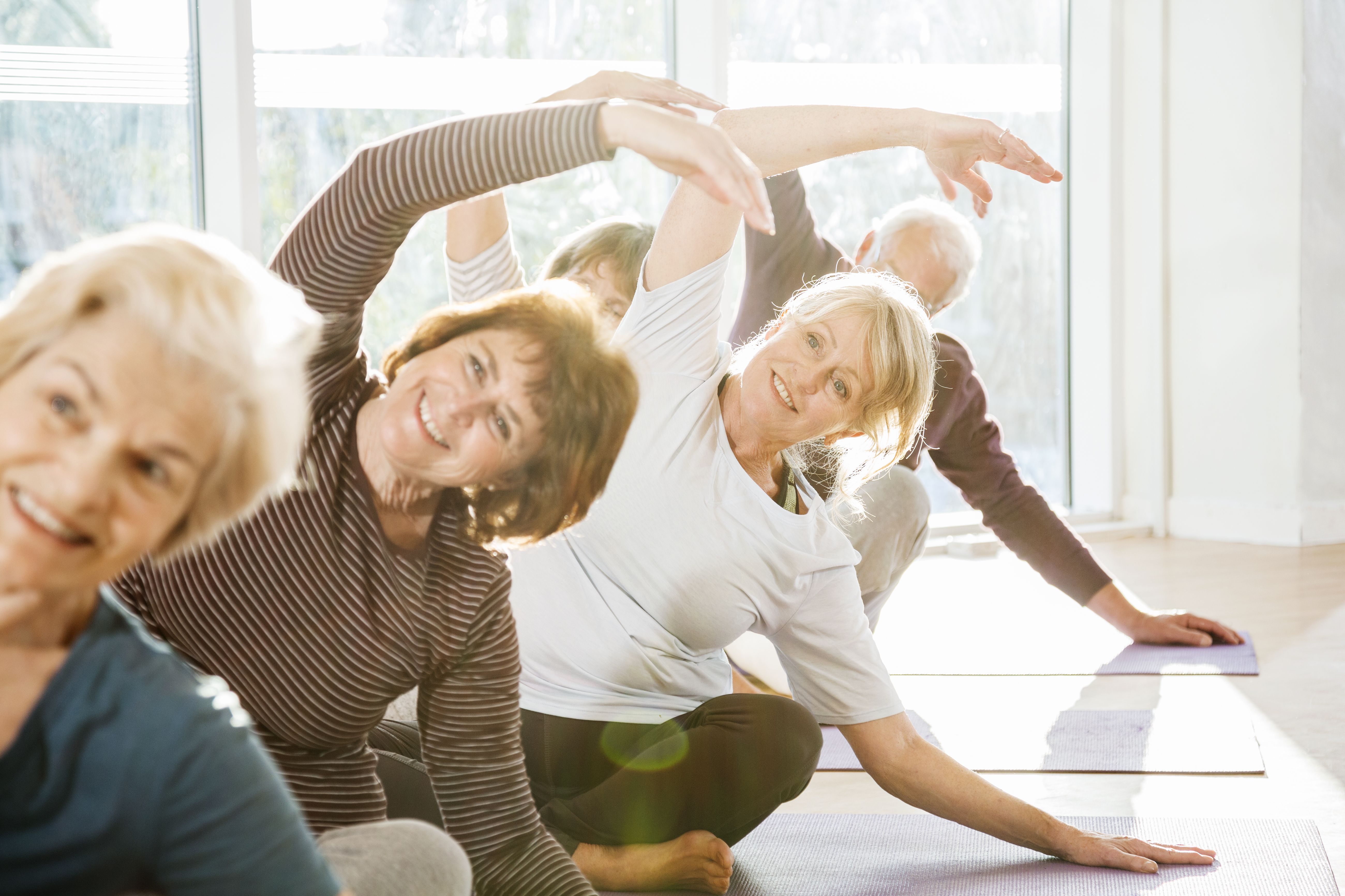 Group of senior women doing stretches in a yoga class.