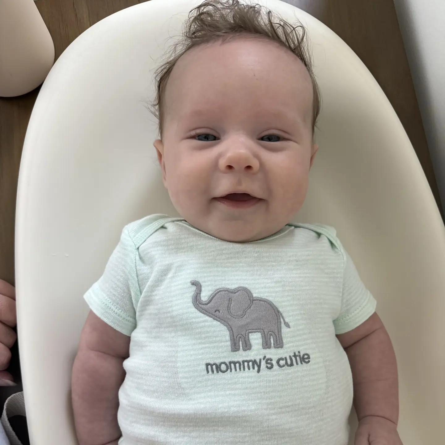 smiling baby wearing a onesie that says "mommy's cutie"