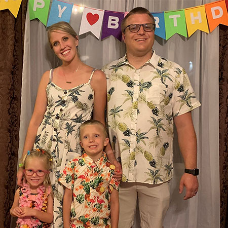 Brooke Lindsay stands in with her family in front a a happy birthday banner