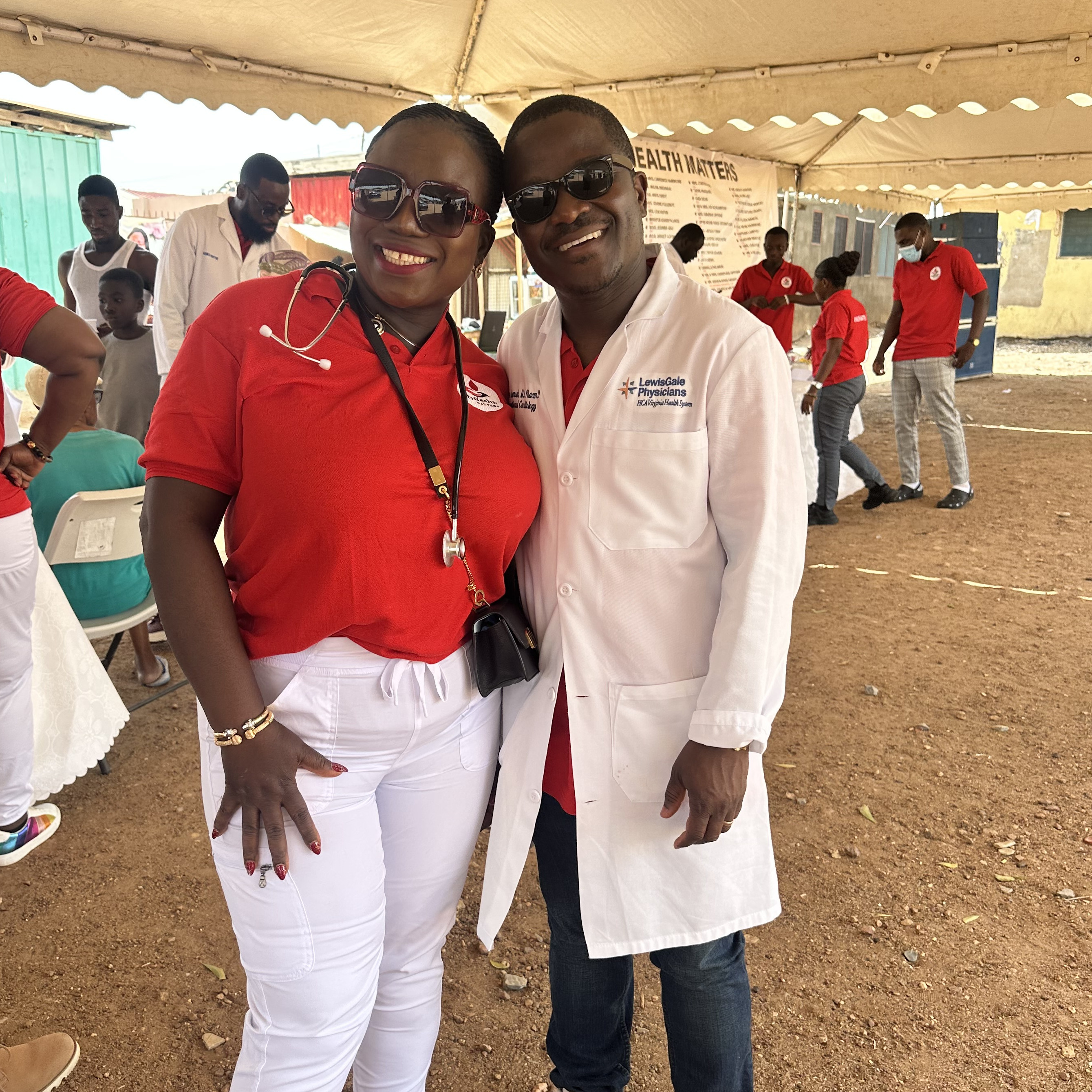 A man and a woman stand side by side. They are wearing medical clothing and accessories.