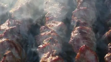 Chunks of steak cooking on a grill.
