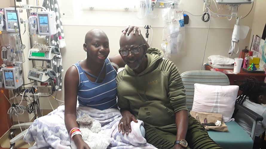 Kalynn Holmes-Butler in the hospital smiling next to her father.