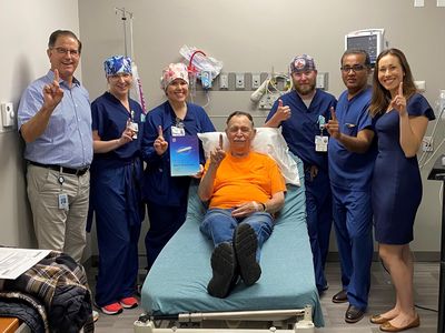 Dale Davies smiles while giving a thumbs up with the cardiology team who helped implant his monitoring device.
