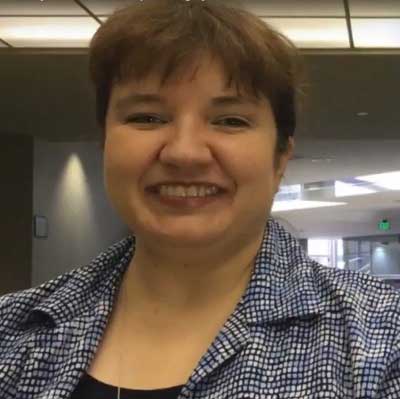Beth Bouchard smiles and is wearing a black and white check shirt.