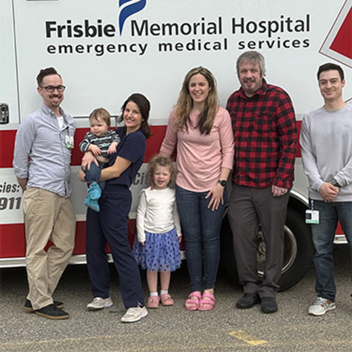 Alison and Jimmy Mathieu with family and friends standing in front of a Frisbie Memorial Hospital ambulance.
