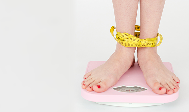 A woman's feet bound by measuring tape, while standing on a scale.