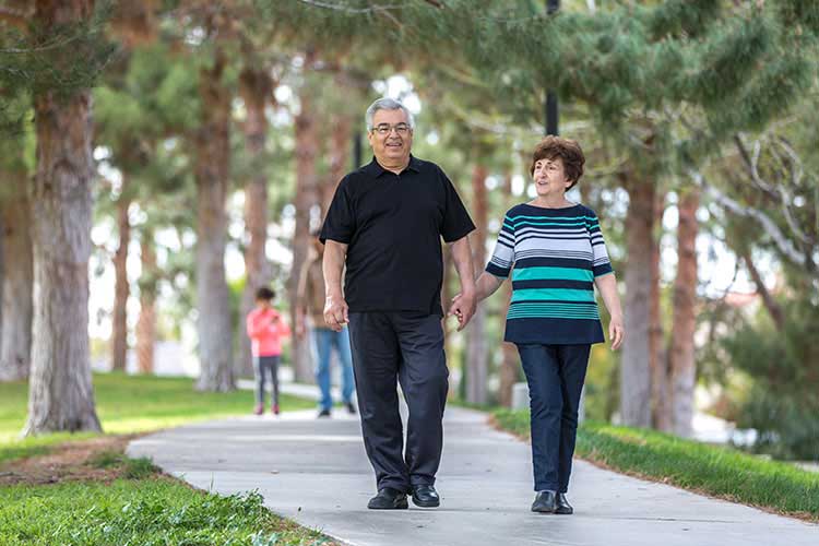 James and Trudy walking hand in hand along a path in the park.