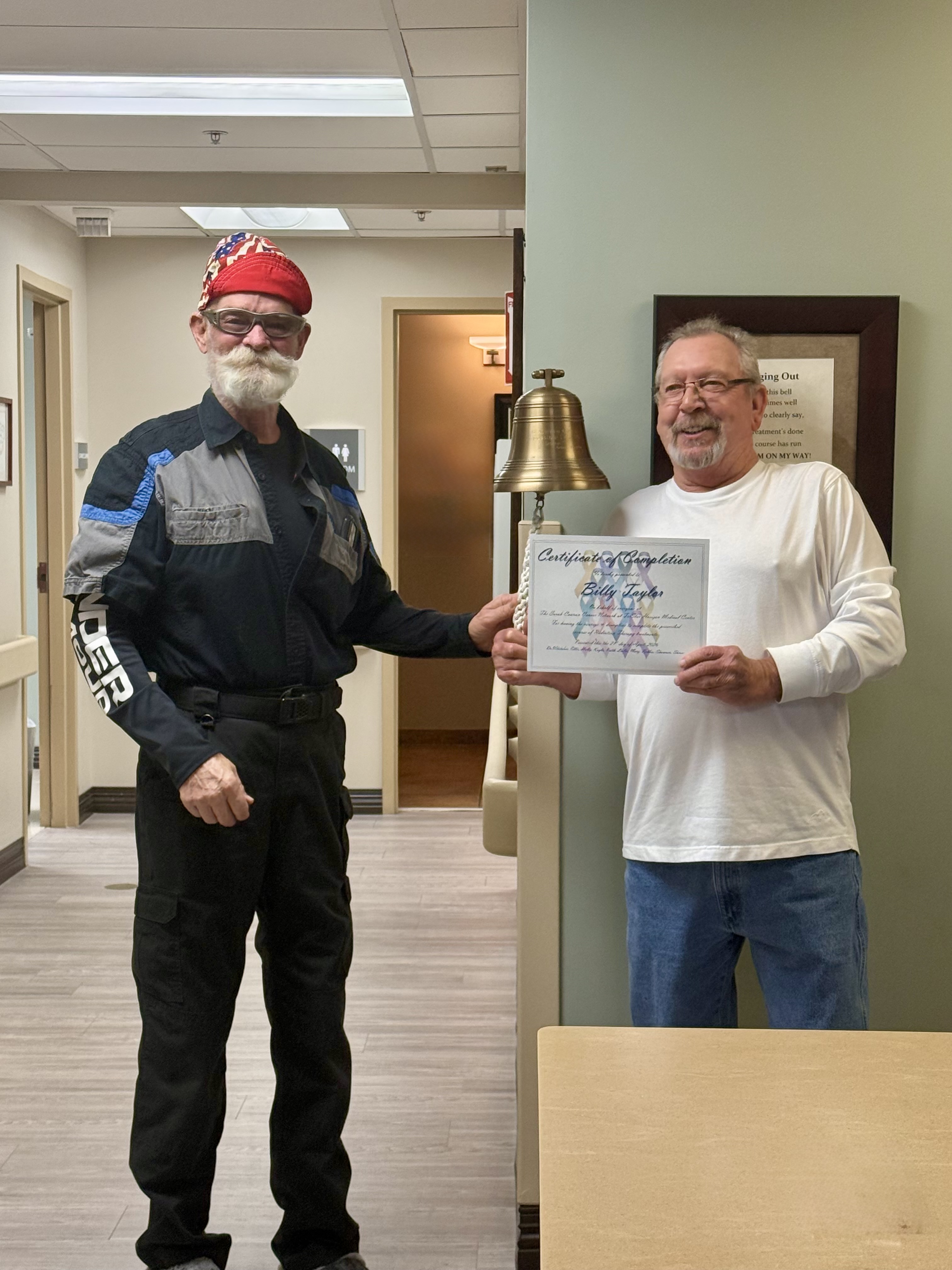 Randy and Billy next to the bell that is rung when treatment ends