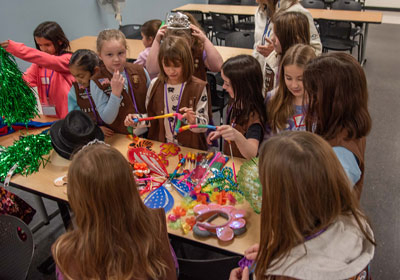 A group of girls standing around a table working on a craft.