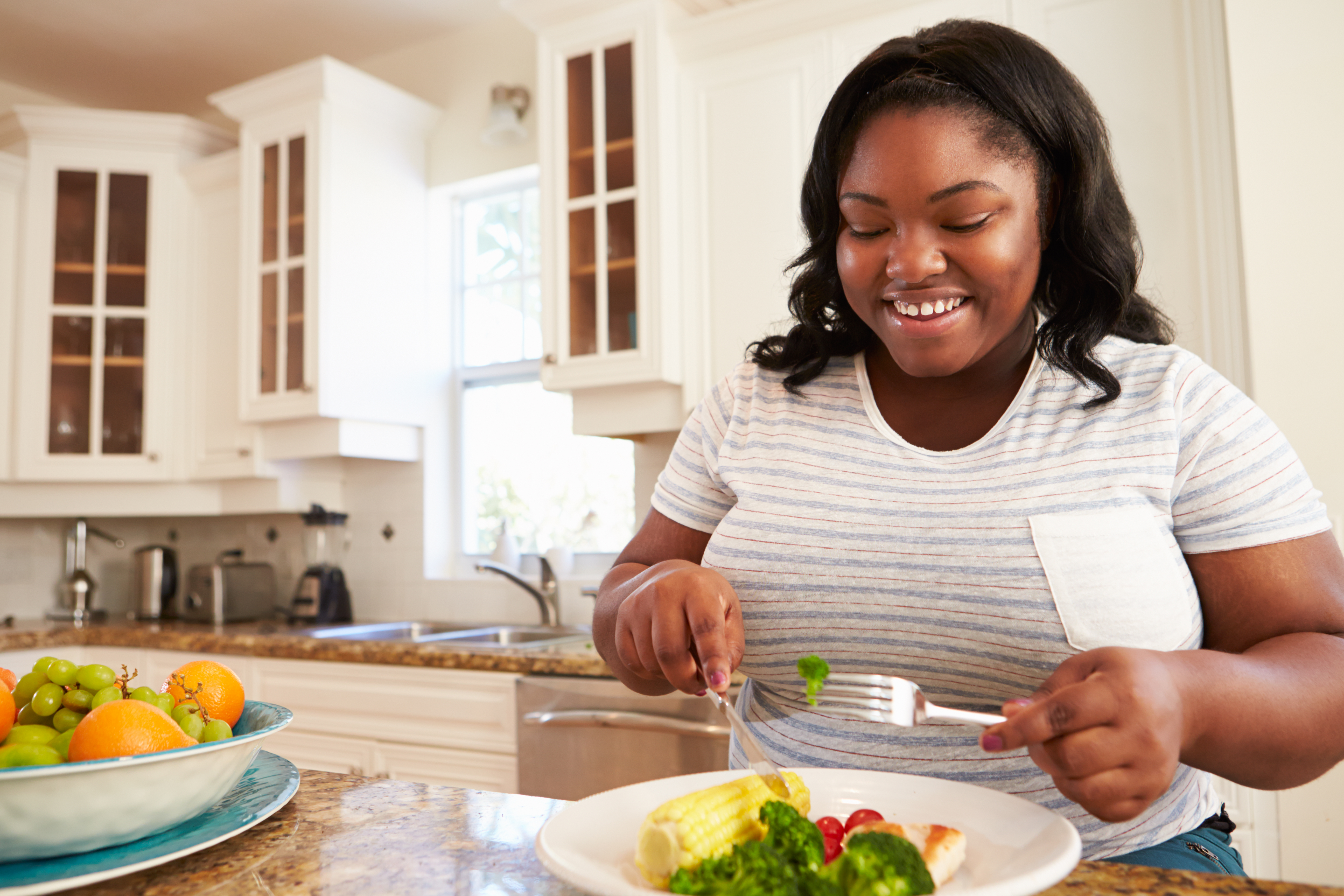 Woman eating a healthy meal in a kitchen.