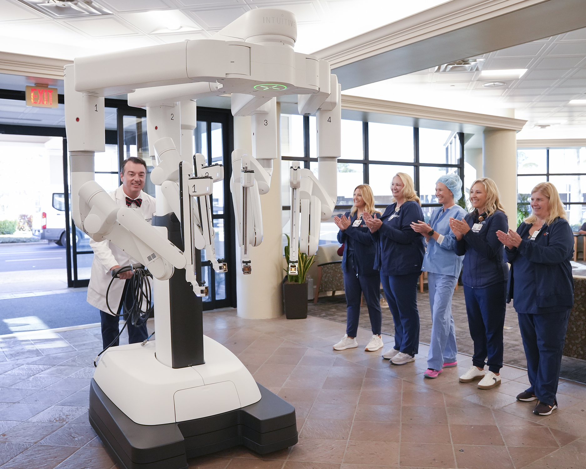 Doctor pushes robot with smiling nurses.