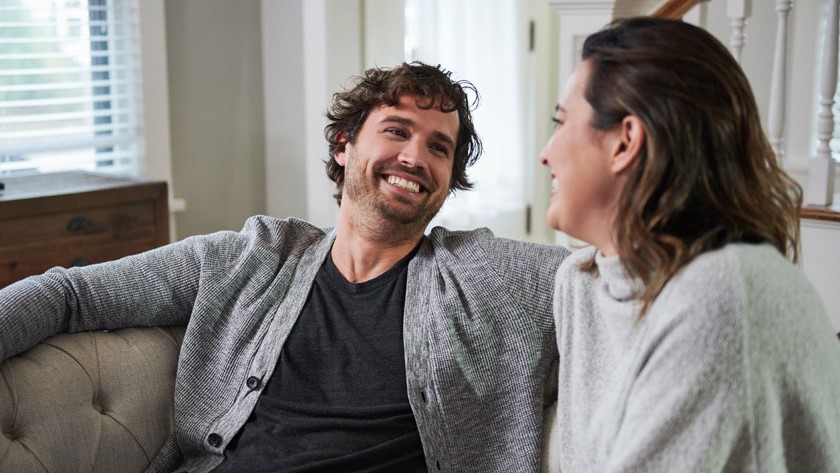 A happy man and woman are laughing on a couch