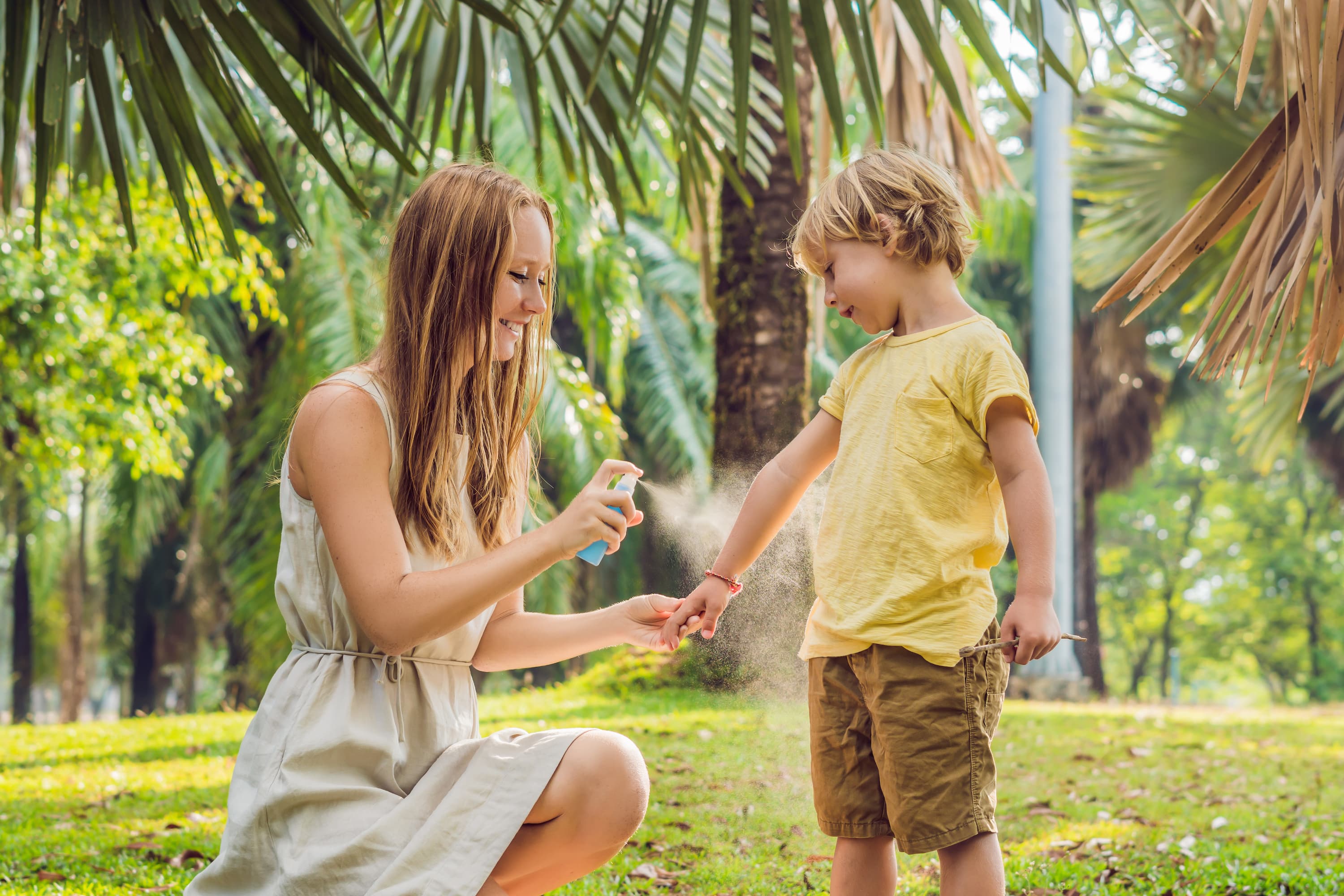 A mother applies insect repellent to her son’s arm.