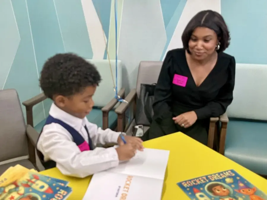 Young boy Payton seated at table with his mother.