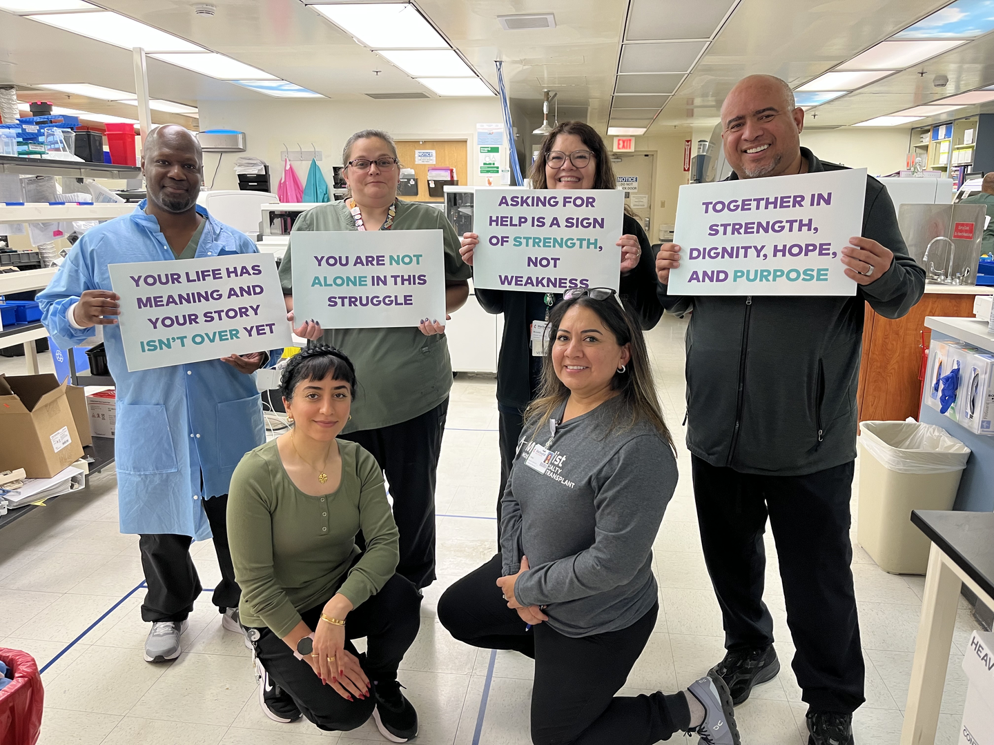 Methodist team members holds signs of encouragment on World Mental Health Day.