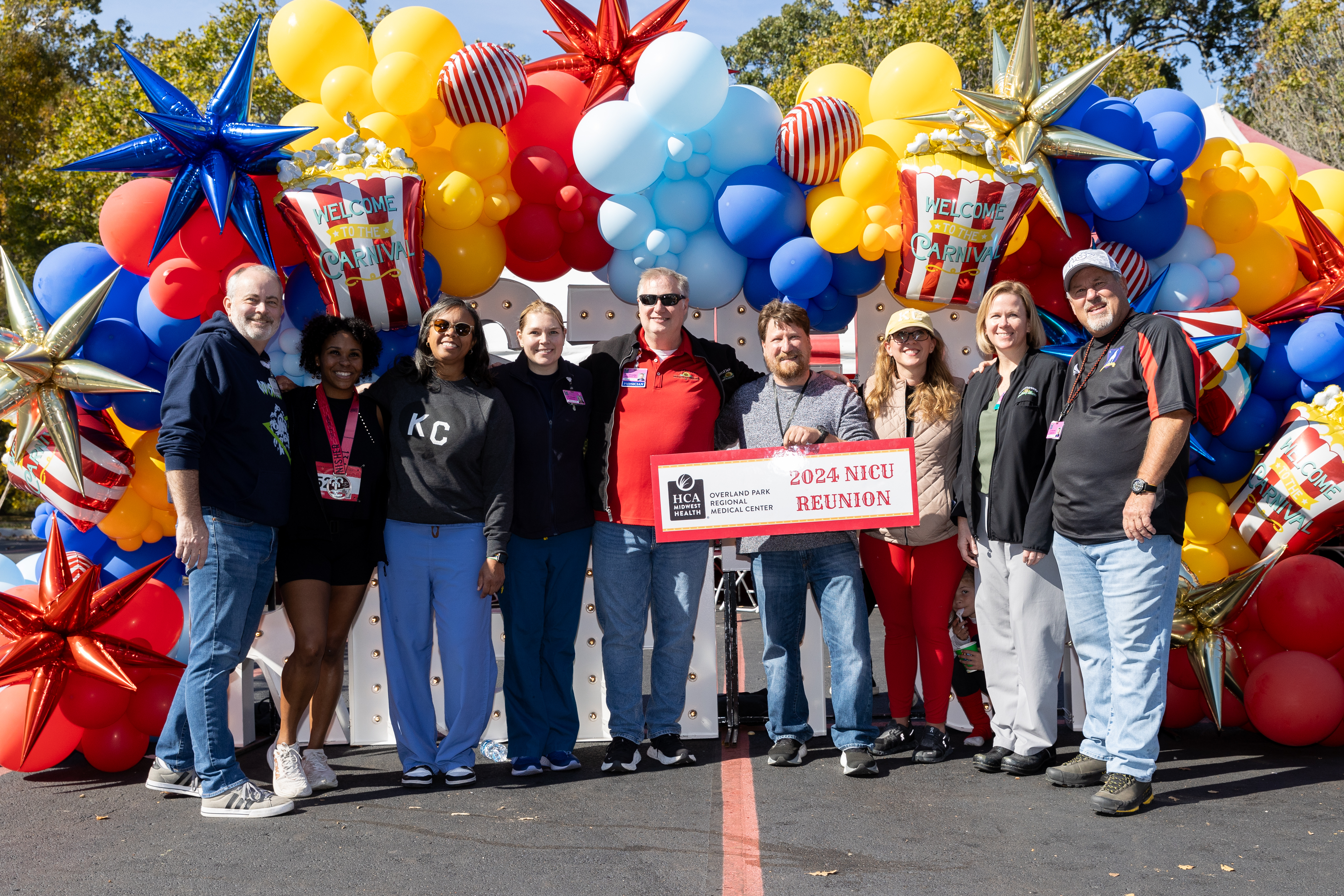 The Neonatologists and NICU caregivers pose reuniting with families and patients under blue, red, yellow, silver, and white balloons