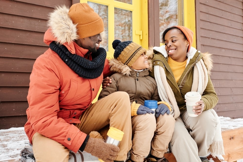 A family dressed in warm clothing, enjoying the winter weather on the porch.