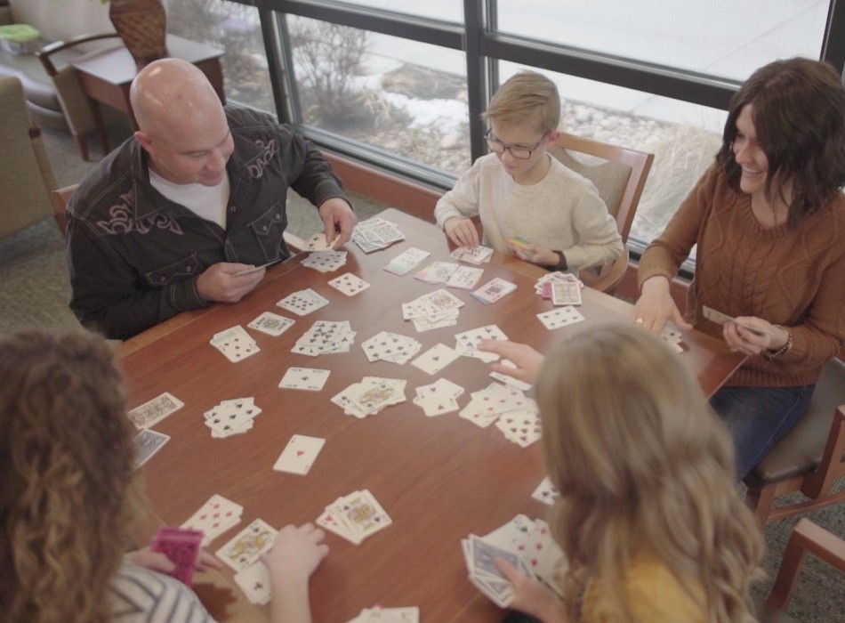 Sandi Mason playing cards with her husband and children.