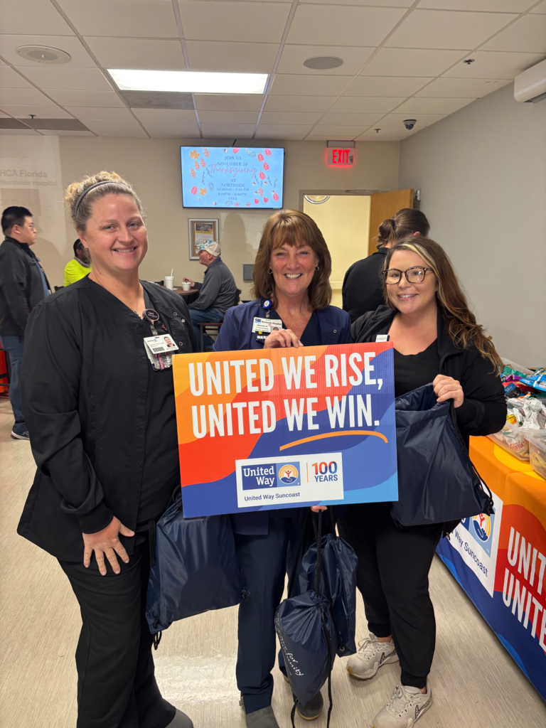 Northside team members holding sign that reads "United we rise, united we win."