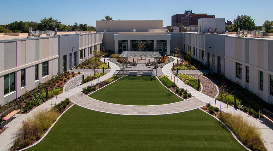 Wesley Rehabilitation Center courtyard, a grass couryard with wavy paved walkways and floral landscaping.