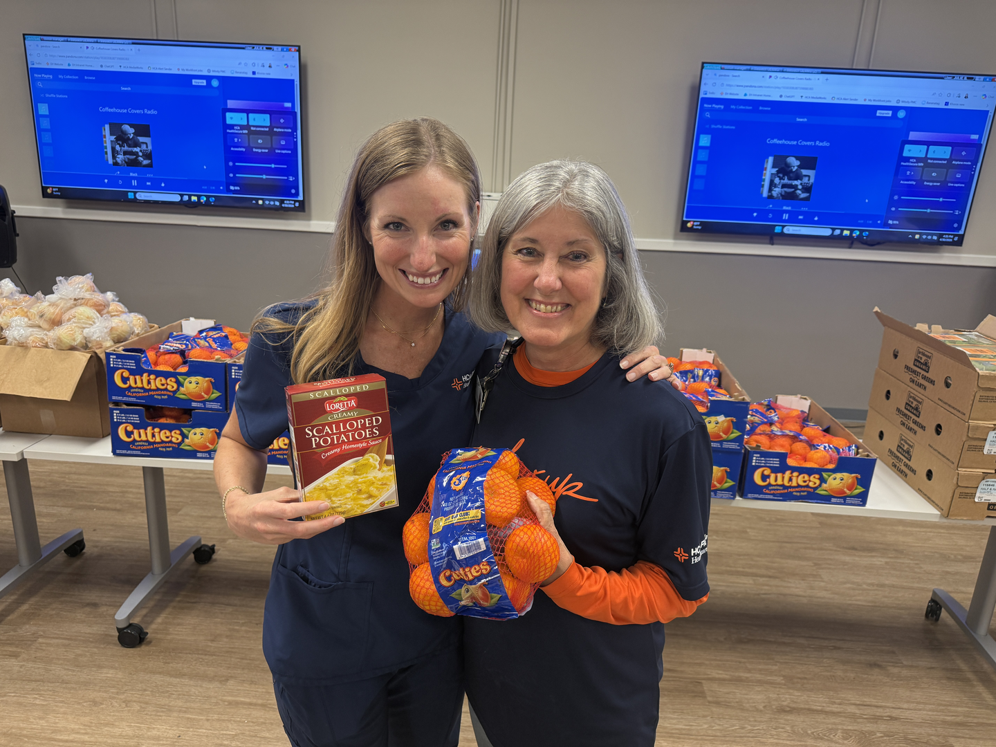 Chief Nursing Officer Nicole Carr and Nurse Supervisor Linda Keller hold donated food items while supporting a community food distribution effort
