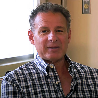 Sal Lucido smiles for the camera, wearing a black and white plaid shirt.