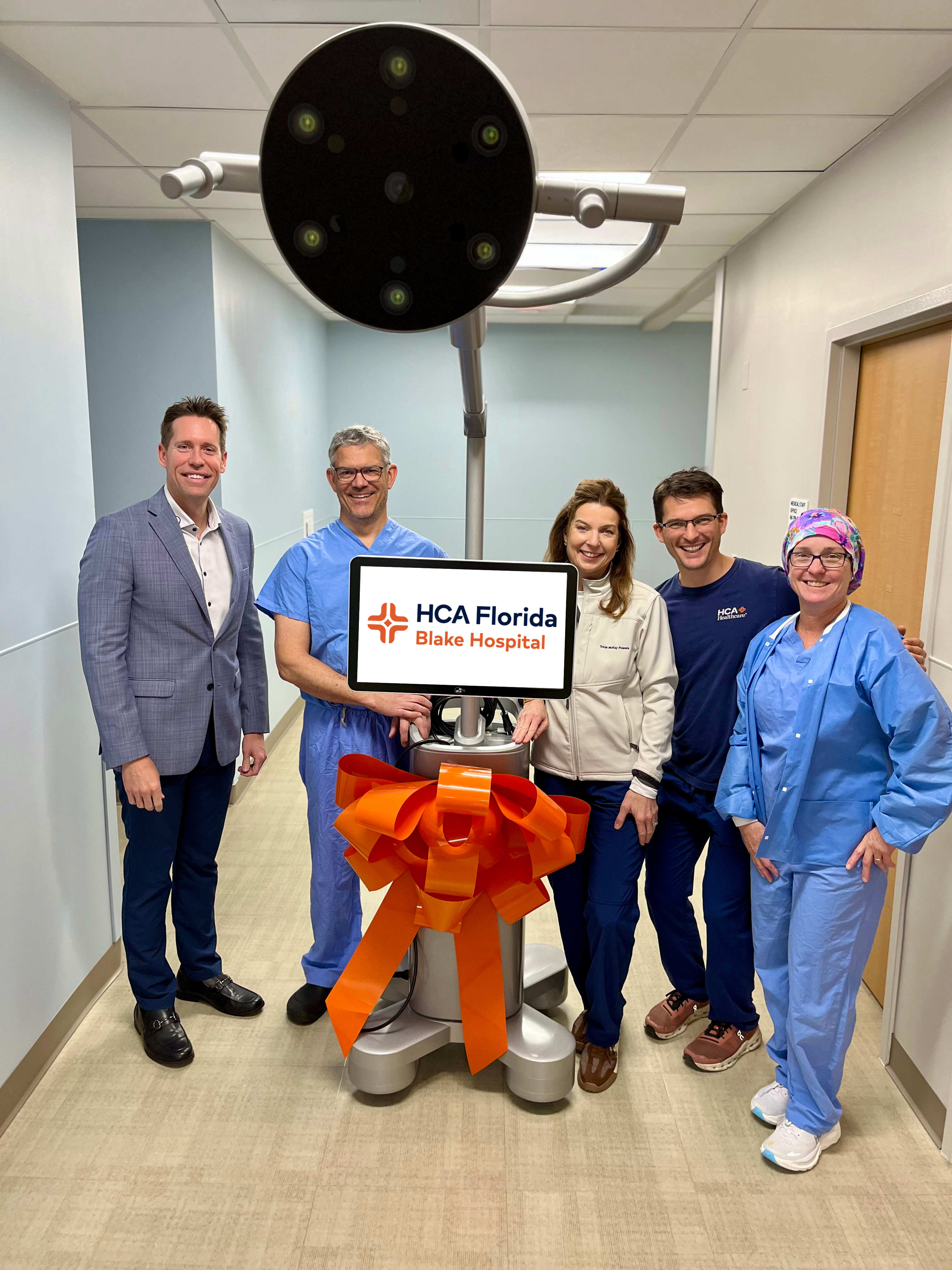 Blake Hospital colleagues stand proudly beside the new robotic surgical equipment.