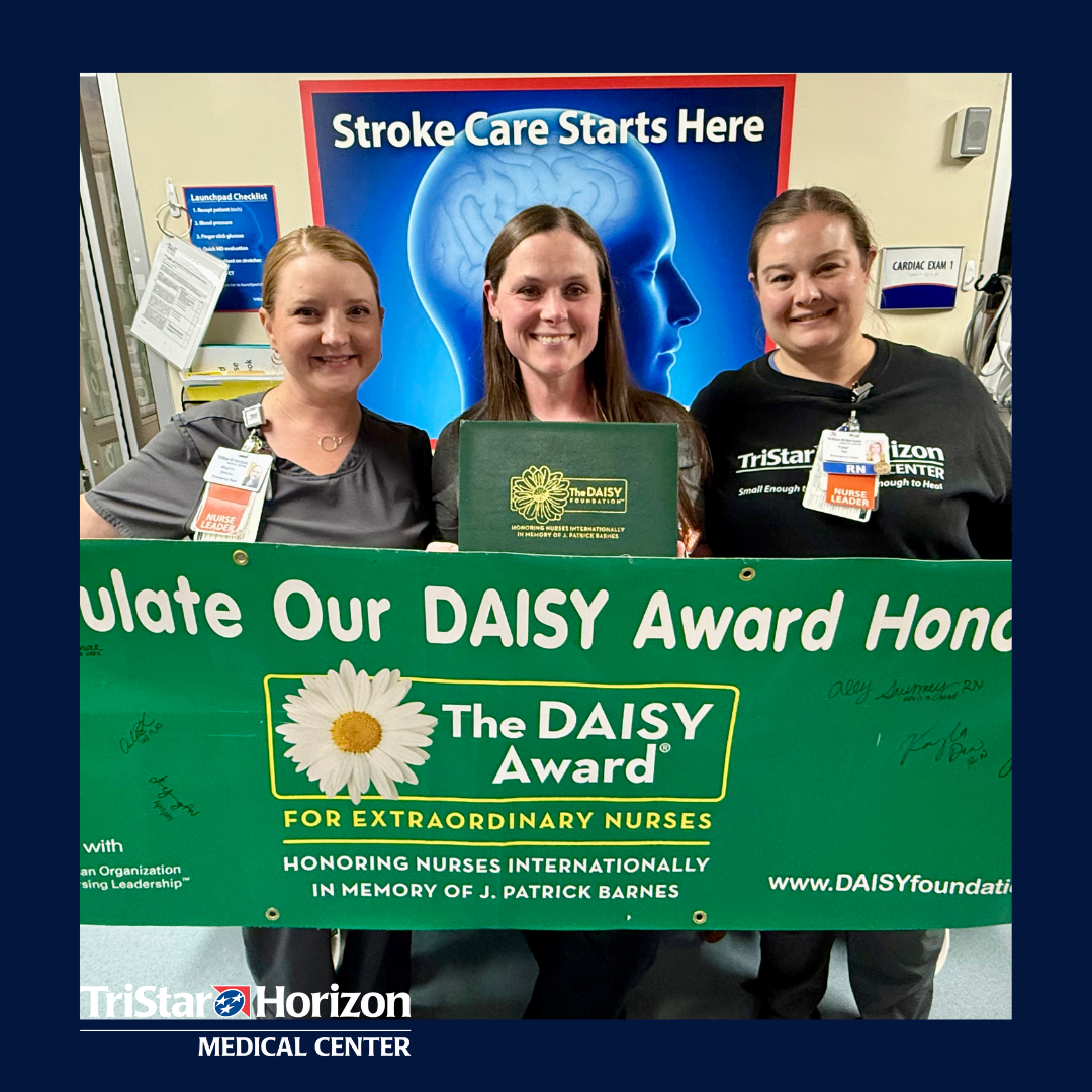 Amber surrounded by 2 peers holding DAISY award banner and award