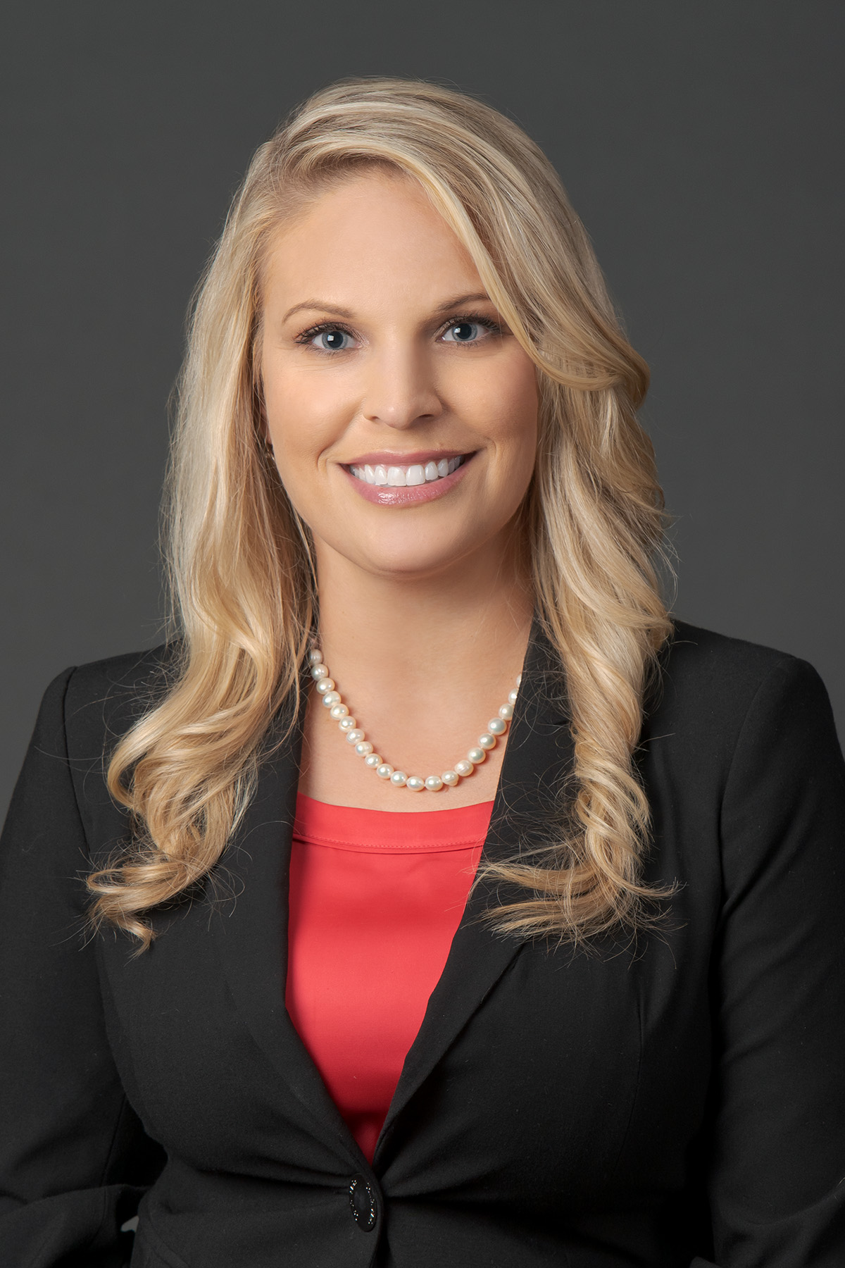 The new CFO for Timpanogos Regional Hospital, Daly Standish, dressed in a red blouse and black blazer, poses and smiles in her professional headshot photo.