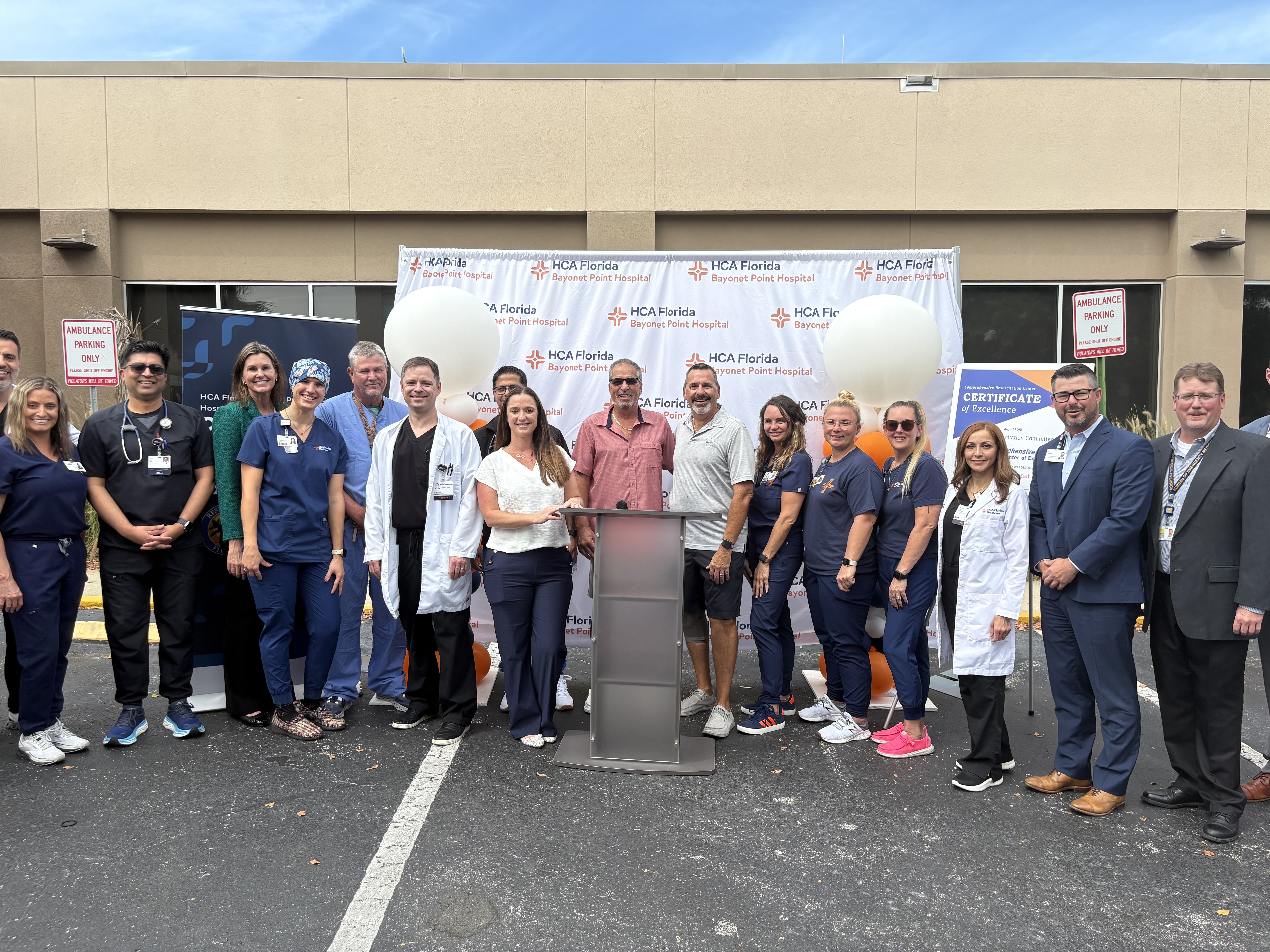 Team standing in front of Bayonet Point Hospital banner.