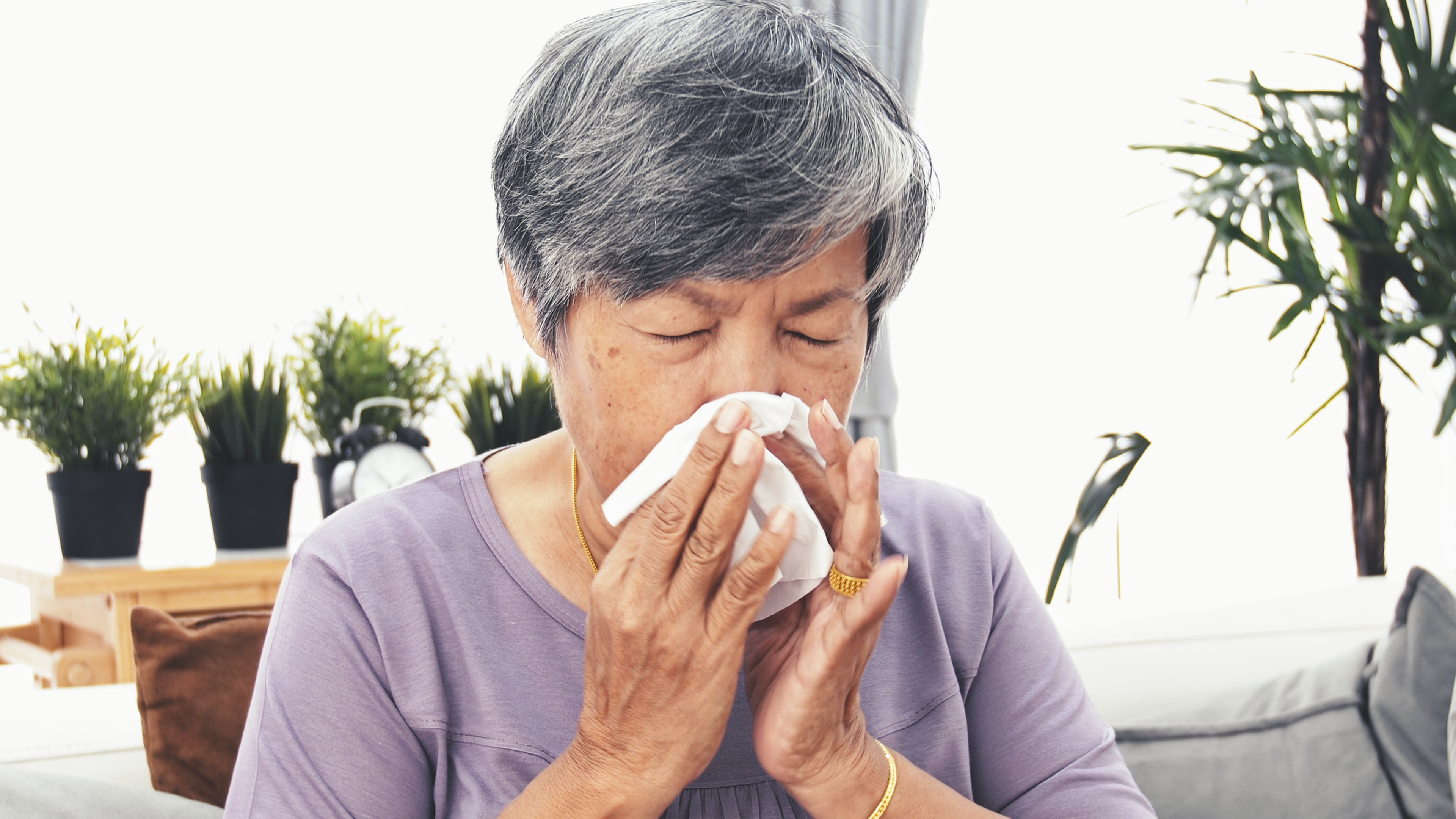 Woman blowing her nose into a tissue.