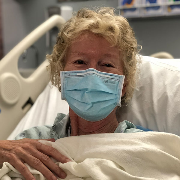 Deirdre Lopez Marquez in her hospital bed, wearing a mask.