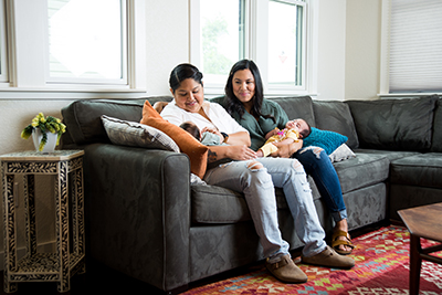 Vanessa Rodriguez and Doctor Elizabeth de la Garza holding Vanessa's babies on a couch.