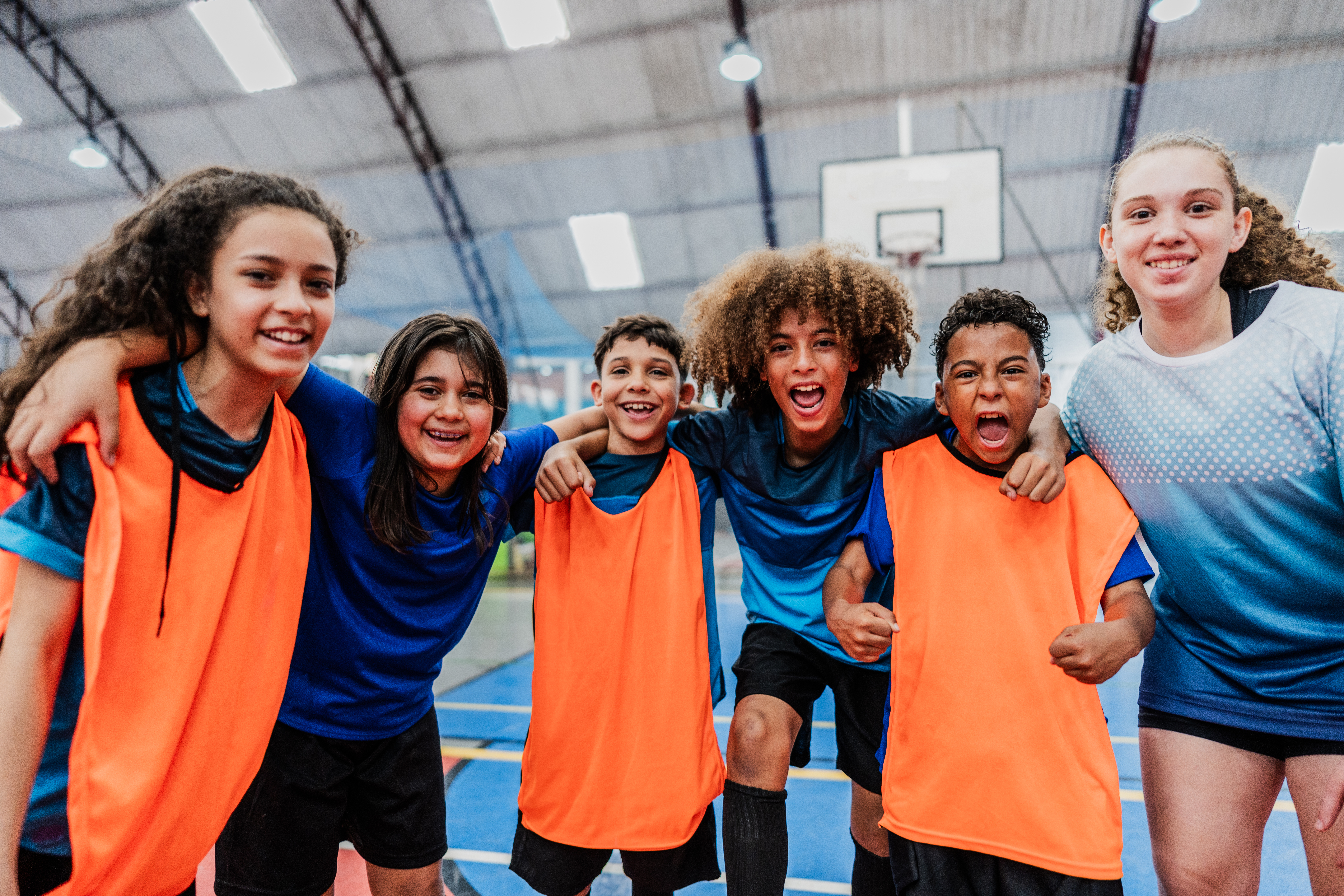Youth coed sports team smiling and hugging.