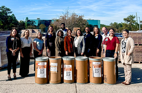 Hospital staff gathering around donation barrels of food. 