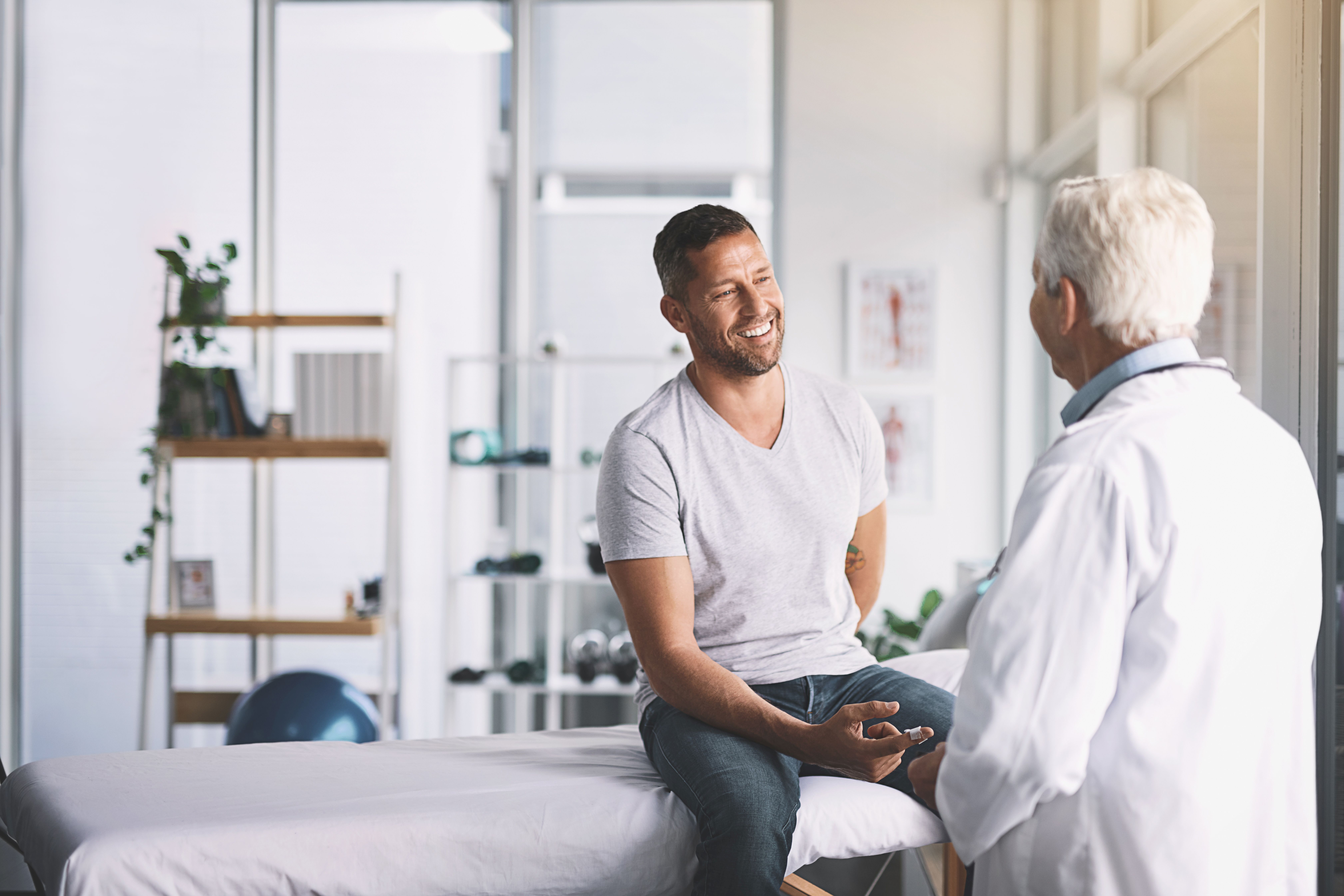 Male sitting speaking with doctor in office