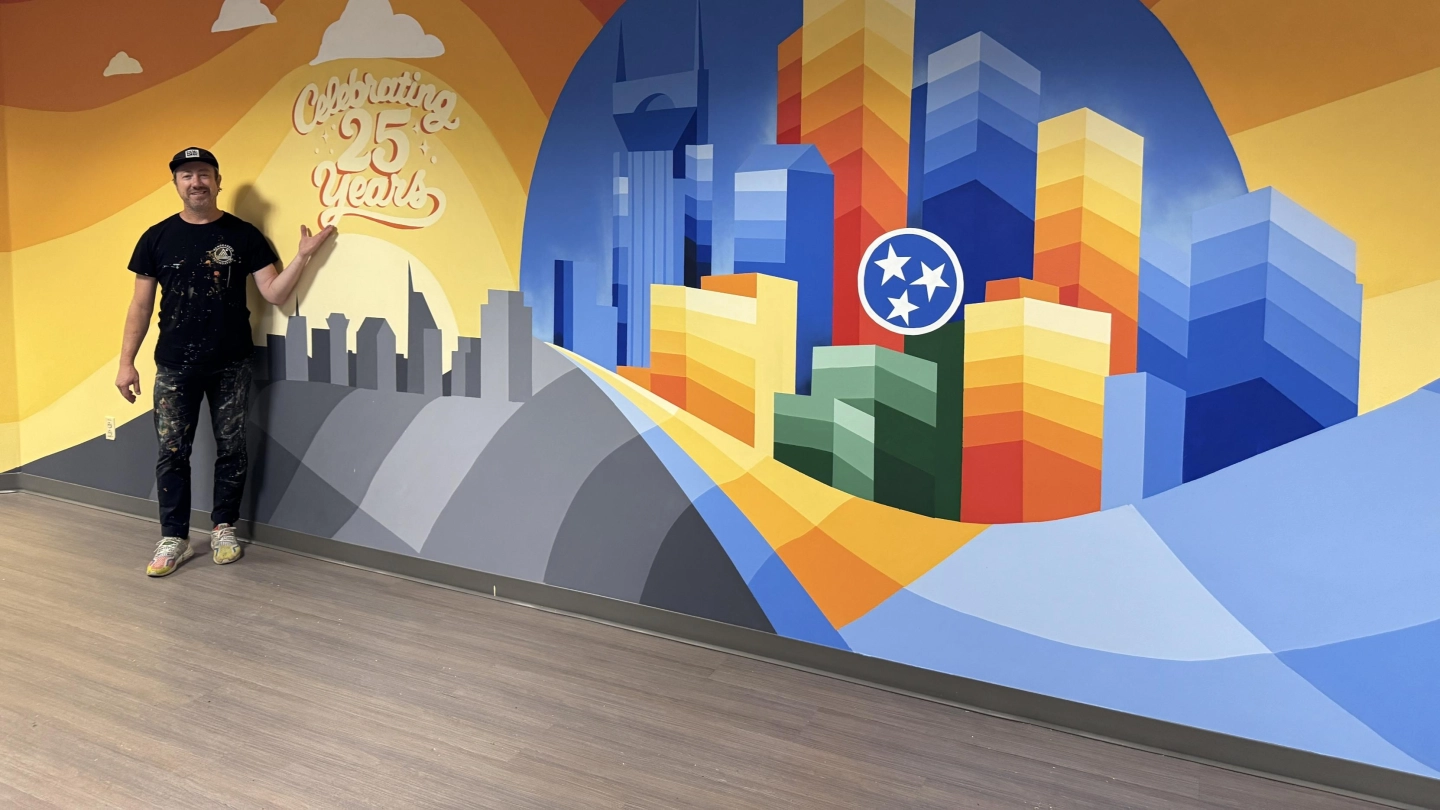 Artist Nathan Brown standing in front of the mural he created.