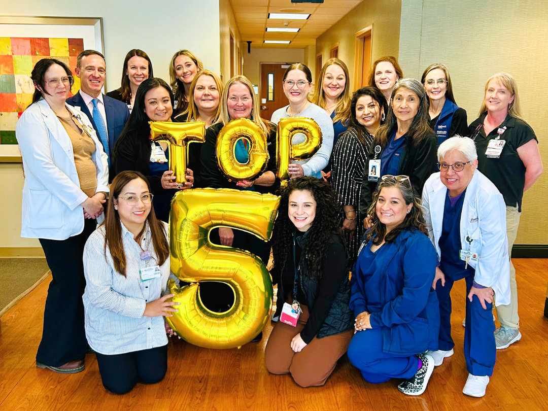 Methodist hospital physicans and staff posing for group photo with balloons spelling out T-O-P-5.