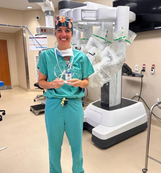 Dr. Amy Alexander holding award in front of surgical robot