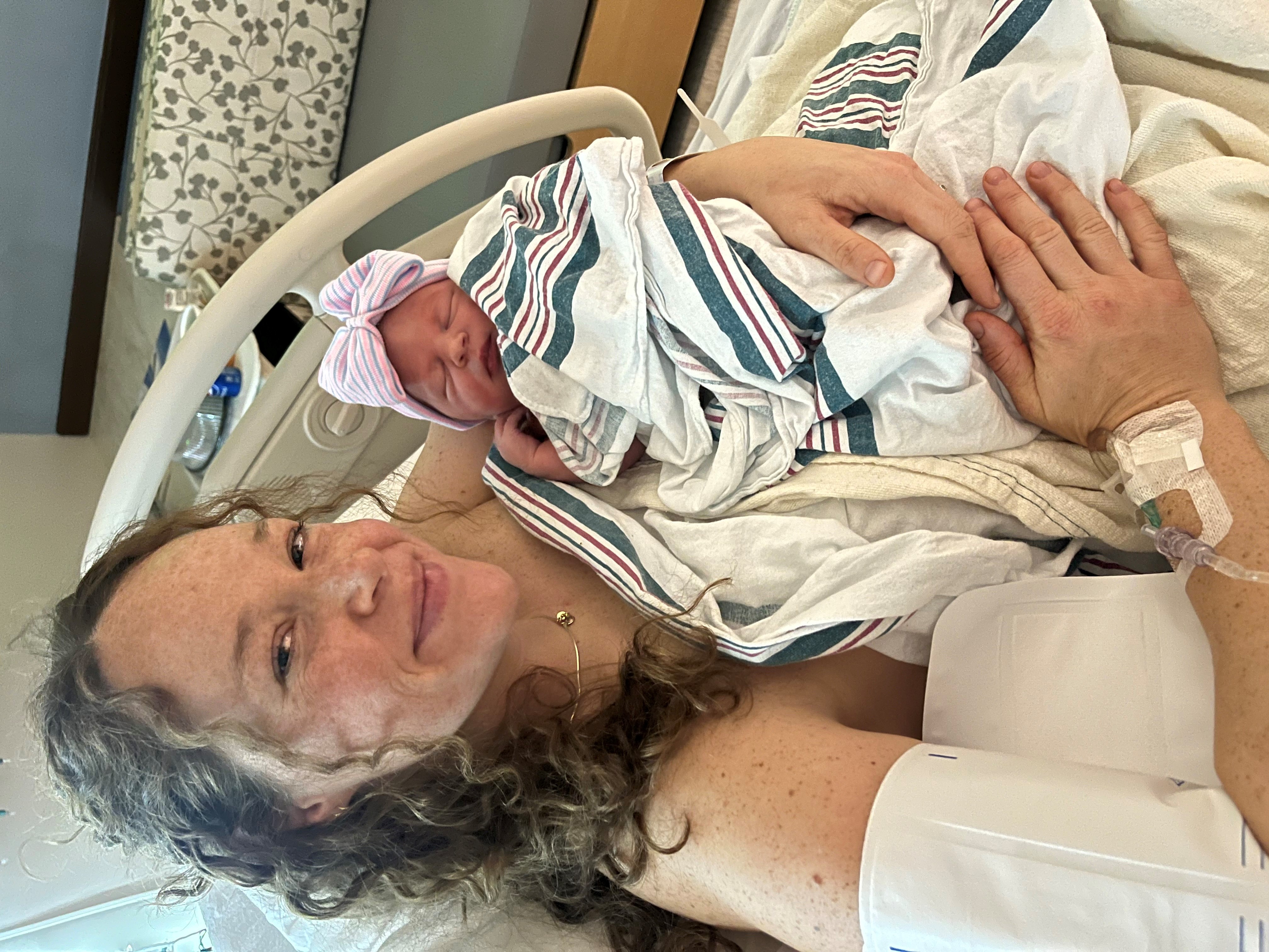 Sarah smiles, holding her newborn baby at Henrico Doctors' Hospital