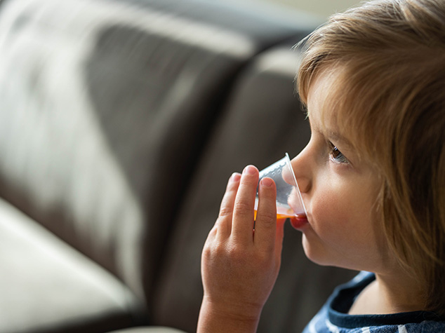 A child uses a dosing cup to take liquid medicine.