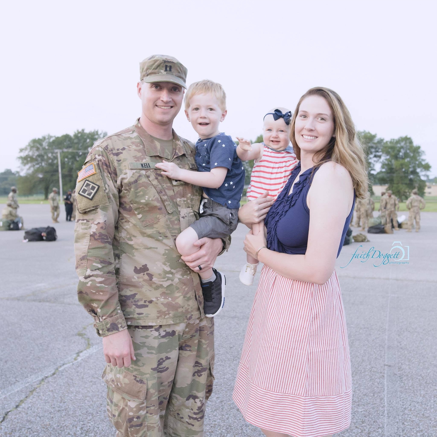 Alex Kell holding her daughter and standing next to her husband holding their son.