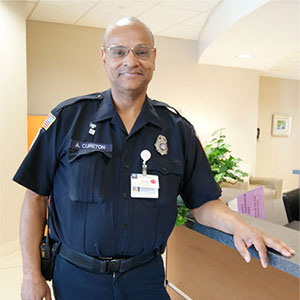 Andre Cureton leaning against a hospital desk in his police officer's uniform.