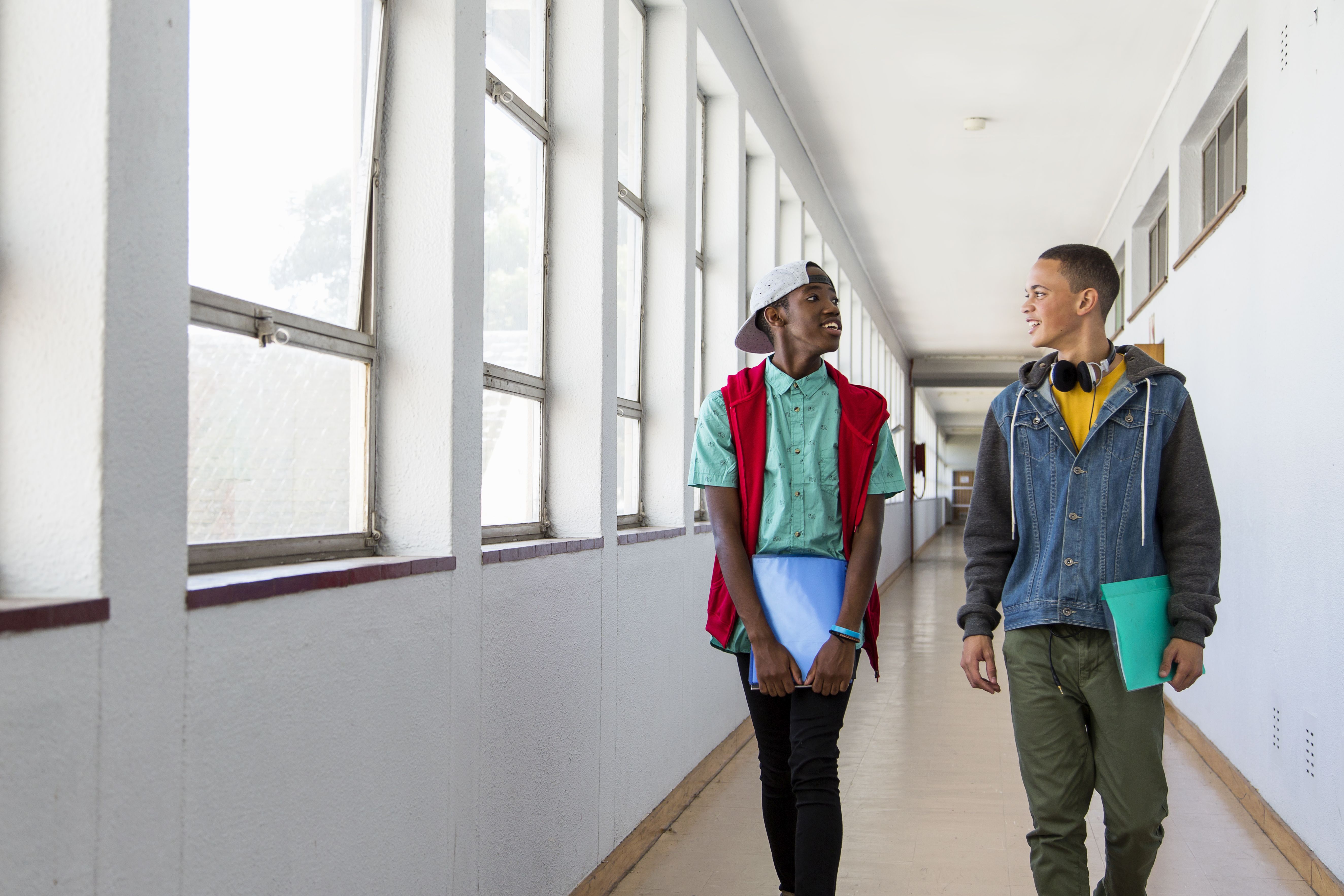 Two school students walking down hallway, chatting