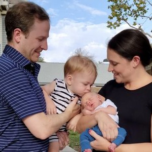 Couple Kari and Cullen Brown embrace their two sons in a candid family portrait outdoors.