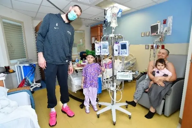 Spurs forward Sandro Mamukelashvili is all smiles with the patient and the patient's family.