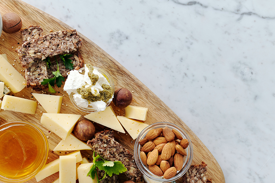 Charcuterie board with snack bread, cheeses, honey and nuts.